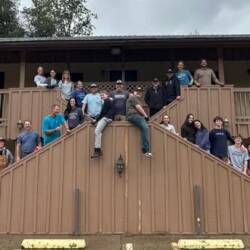 Group of around 20 volunteers posing in front of the former Miner's Motel in Jamestown CA. The motel is being repurposed to low income housing.