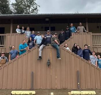 Group of around 20 volunteers posing in front of the former Miner's Motel in Jamestown CA. The motel is being repurposed to low income housing.