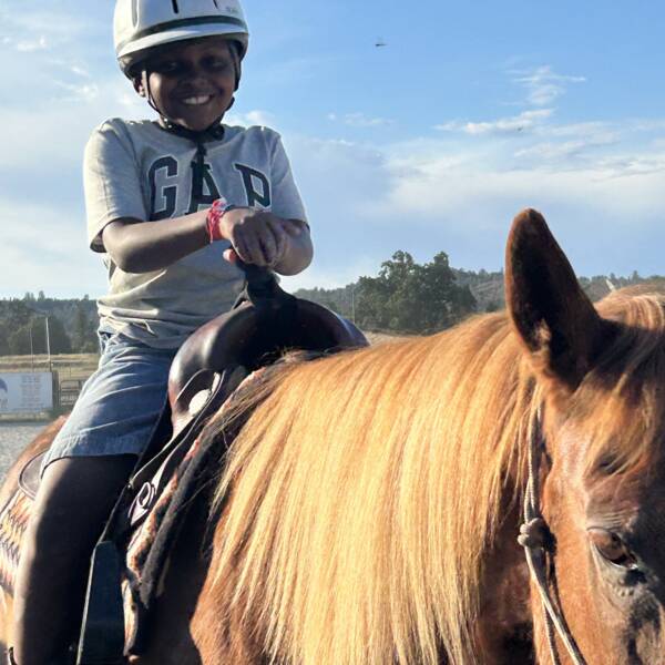 Young boy with a big grin on a brown horse with golden mane